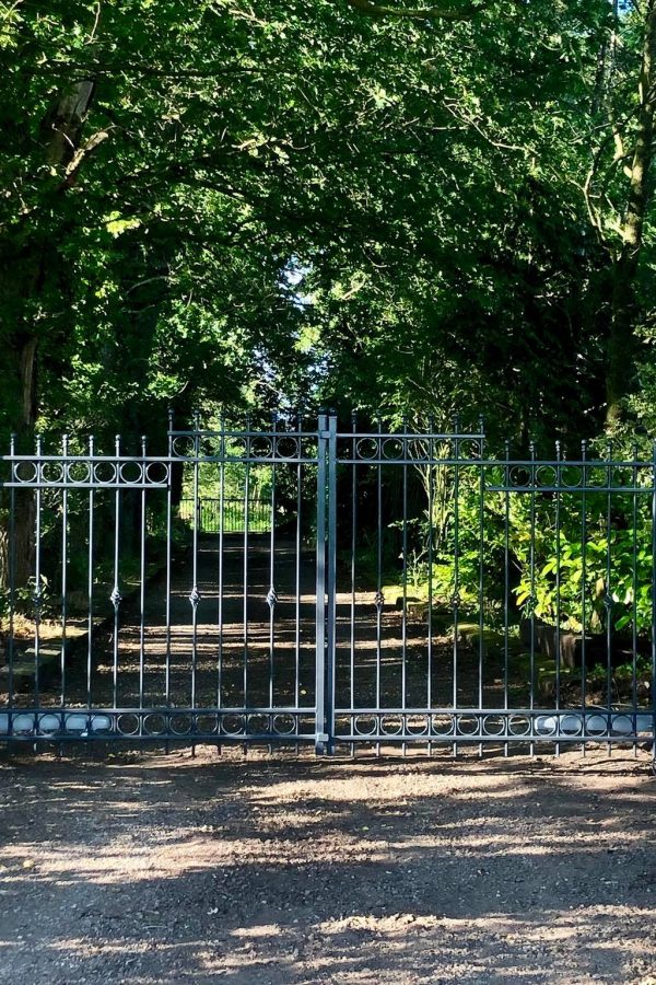 Sierhekwerk bij een mooi beboste oprijlaan